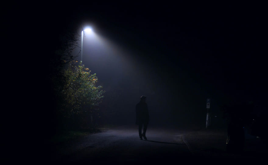 A person walking alone on a dark street at night